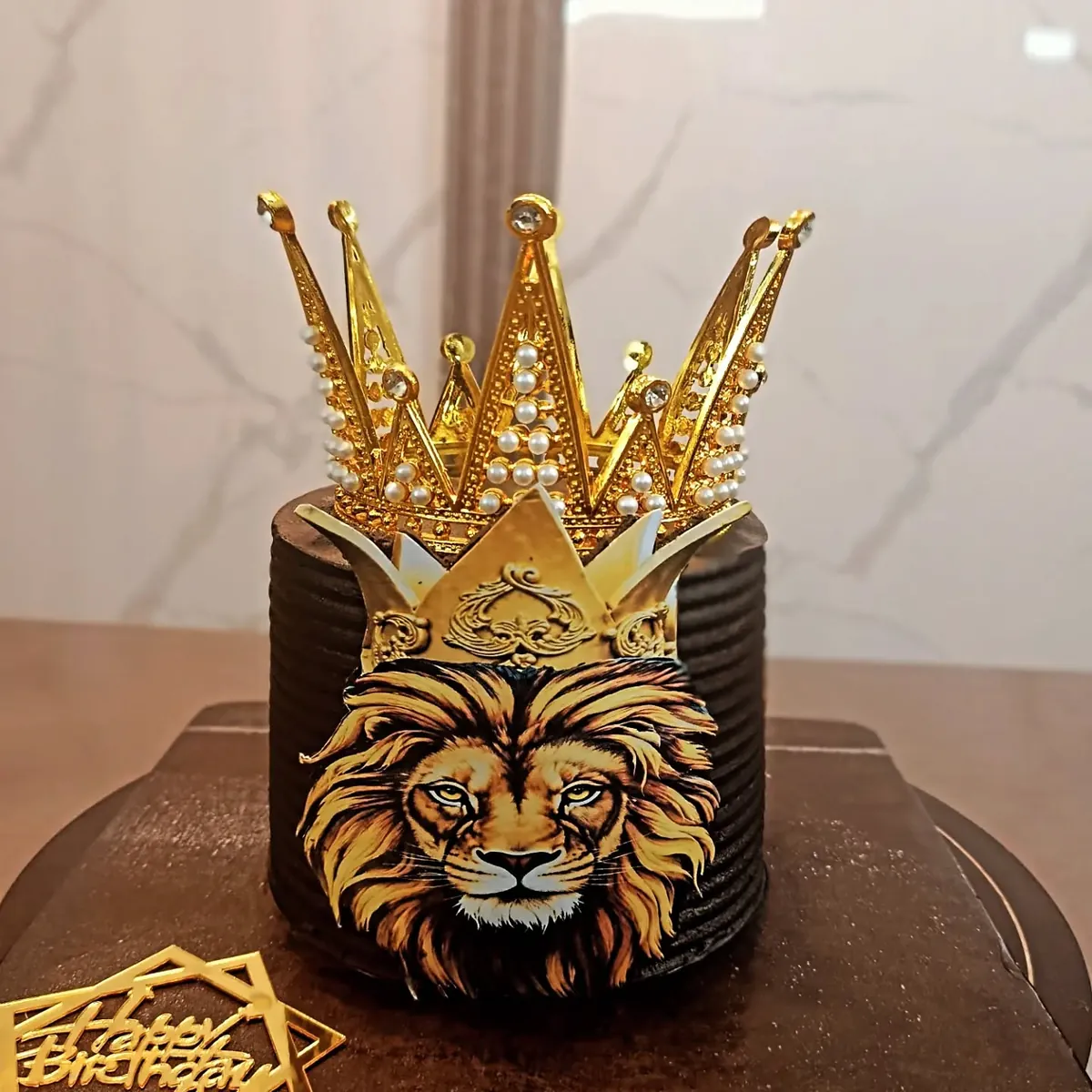 Black and gold lion cake with a gold crown, by Cake's Kingdom
